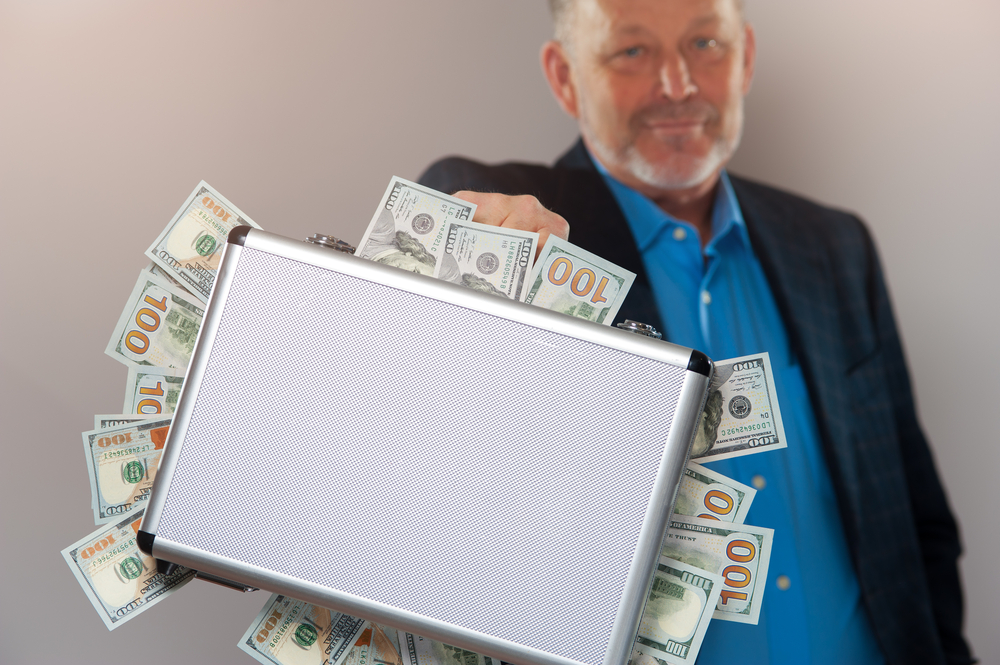 Senior man showing his suitcase full of money